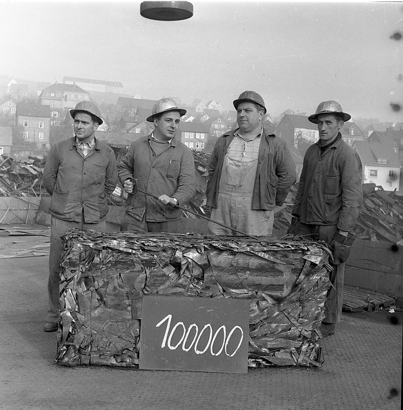Vier Arbeiter mit dem 100.000sten Schrottpaket gepressten Schrottpaket.