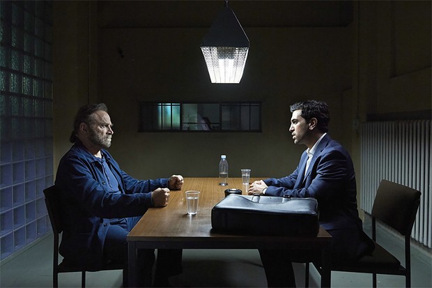 Zwei Männer sitzen sich an einem Tisch gegenüber.