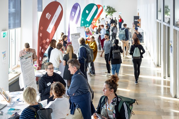 Menschen laufen an Infoständen auf einem Kongress vorbei