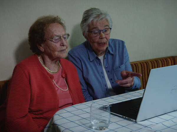 Lenchen Brandenburg (links) und Bernhardine Jütten (rechts) vorm Laptop im Gespräch. Sie schauen zusammen den WDR-Beitrag „Utopia: Brilon im Sauerland