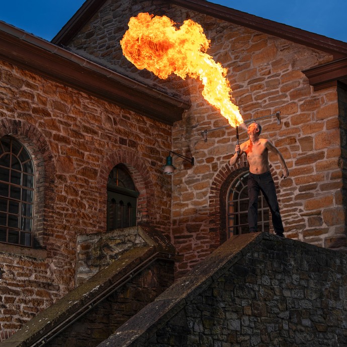 Axel Thiemann beim Feuerspucken während einer Vorführung auf dem Gelände des LWL-Museums Zeche Nachtigall (vergrößerte Bildansicht wird geöffnet)