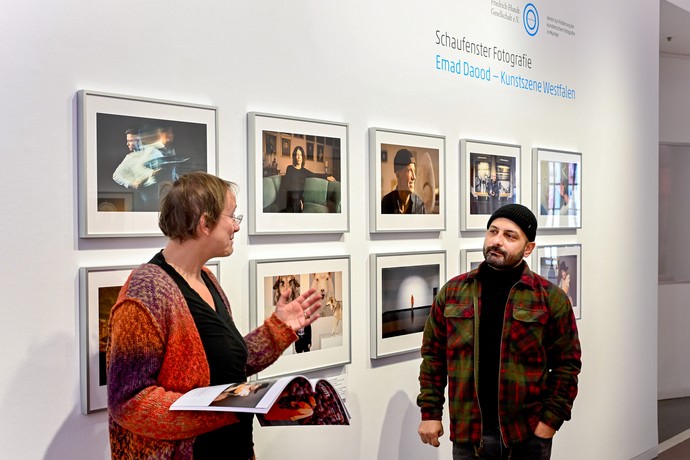 Ricarda Holz und Emad Daood vor Fotografien der Ausstellung.