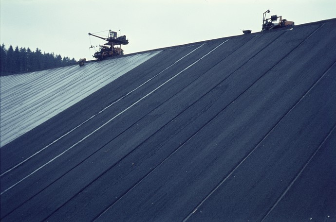 Die Innenseite des Damms wird mithilfe von Krananlagen abgedichtet. Die Innenseite des Damms wird mithilfe von Krananlagen abgedichtet.