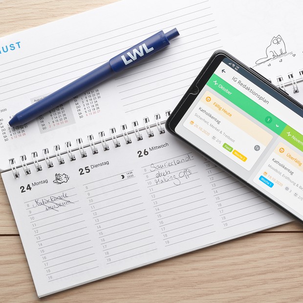 Ausgeklappter Tischkalender mit Handy und LWL-Kugelschreiber.