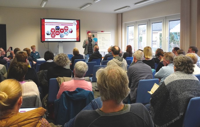 Ein Mann spricht vor Publikum in einem Plenums-Saal.