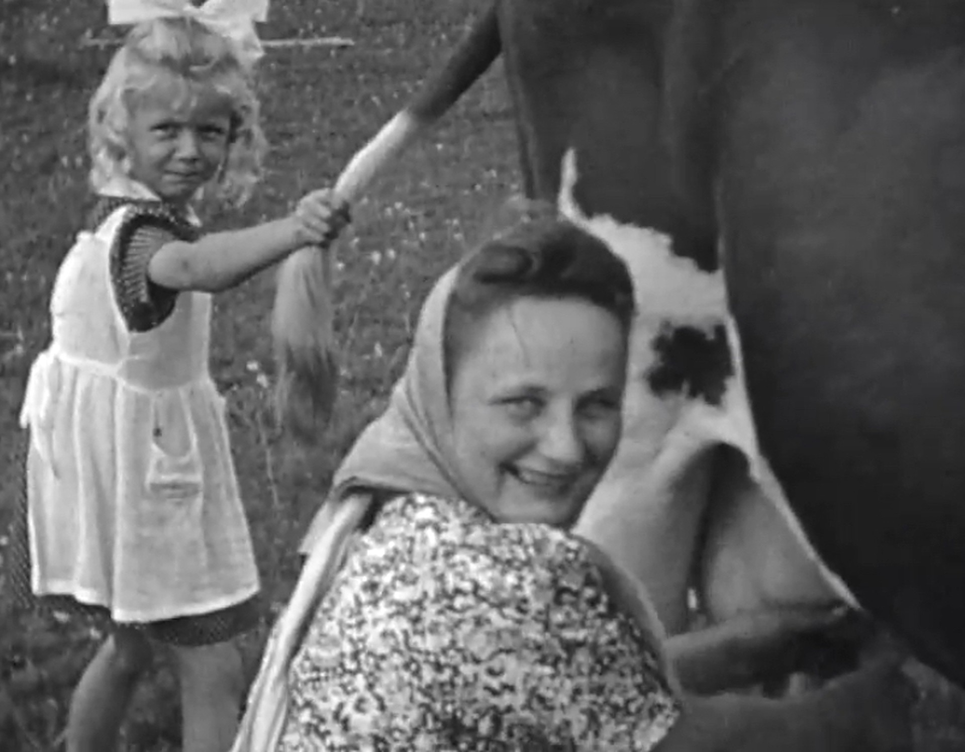 Filmaufnahmen von einer Bäuerin und einem Mädchen beim Melken.