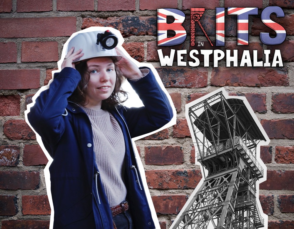 Das Bild zeigt die Moderatorin Jasmine Sainsbury vor einer roten Backsteinwand neben einem Förderturm.